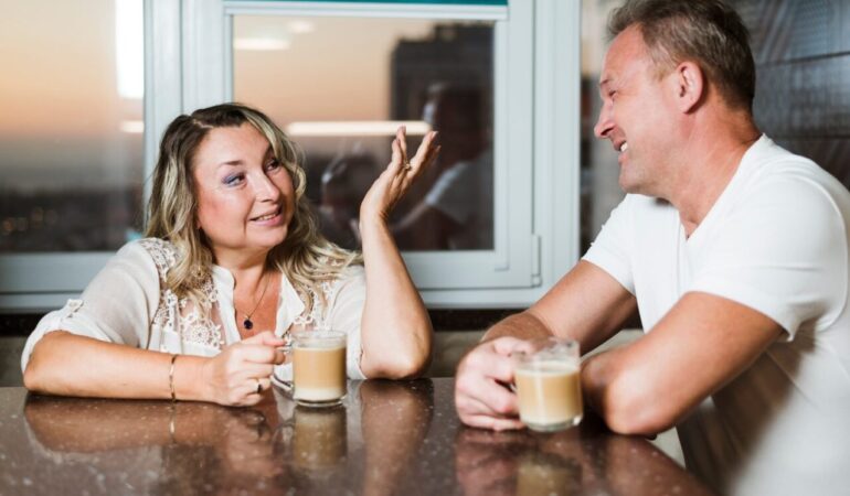Deux seniors discutent autour d’un café dans un espace convivial.